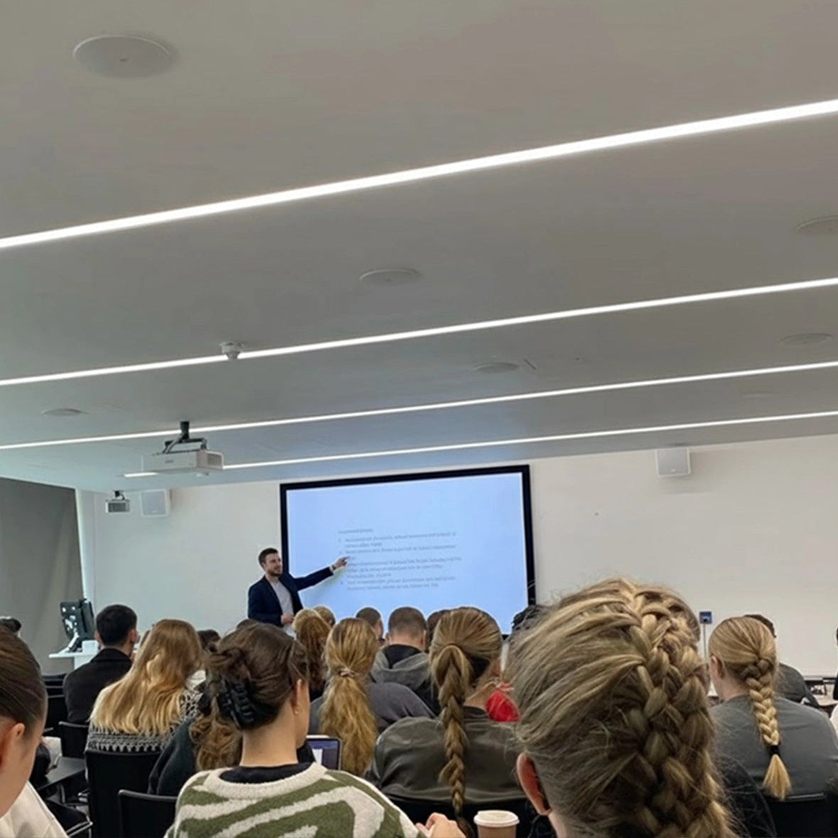 Person giving a presentation to an audience in a lecture hall.