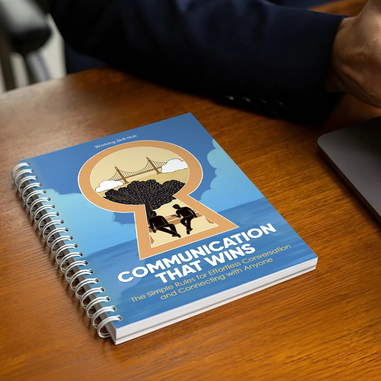 Book titled 'Communication That Wins' on a desk with a laptop