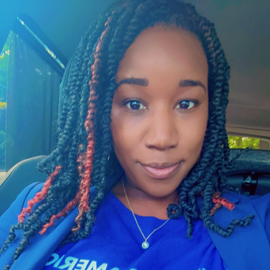 Person wearing a blue sweatshirt with text, sitting inside a vehicle.